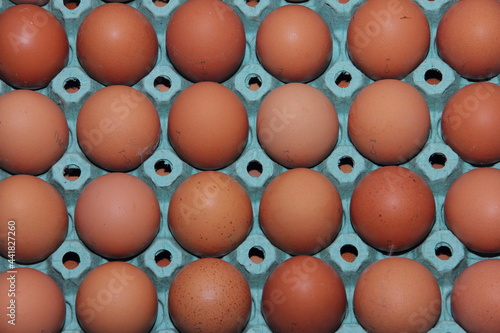 Brown eggs lie in a green paper tray forming a textured background photo