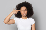 Unhappy young African American woman isolated on grey studio background put imaginary gun to head feeling depressed. Upset mixed race female kill herself suffer from life problems or depression.