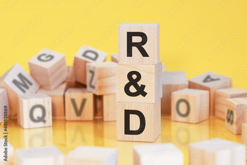 wooden cubes with letters R and D arranged in a vertical pyramid, yellow background wooden cubes with letters R and D arranged in a vertical pyramid, yellow background
