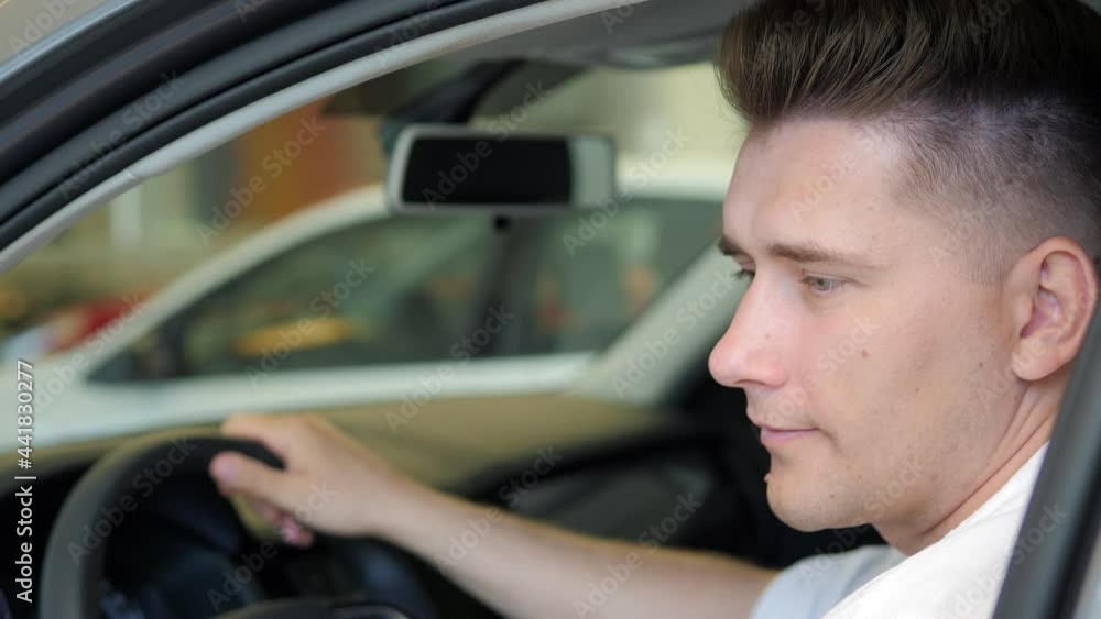 A beautiful European man picks up a car for purchase, examines the interior of the salon. I'm buying a new car. A business person picks up a car for himself. A man is sitting in the salon A beautiful European man picks up a car for purchase, examines the interior of the salon. I'm buying a new car. A business person picks up a car for himself. A man is sitting in the salon