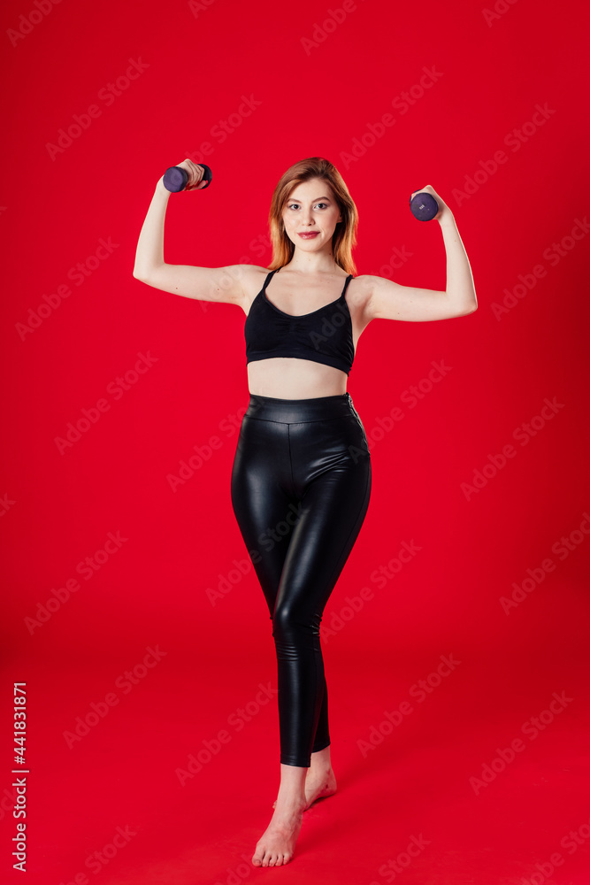 brown-haired girl in black leggings and a T-shirt goes in for sports. on a red background. brown-haired girl in black leggings and a T-shirt goes in for sports. on a red background.