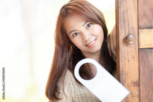 Asian Cute woman hold door tag and smile in front of wood door at outdoor field. photo