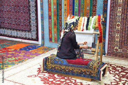 Woman hands weaving carpet on the loom