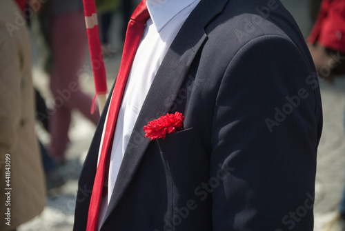 Pessoa com um fato preto vestido, camisa branca, gravata vermelha e um cravo vermelho no bolso do casaco - contestação dos cravos vermelhos - meio ambiente - revolução portuguesa photo