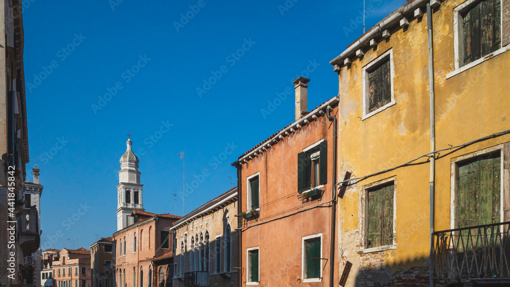 Venetian houses and tower under blue sky in Venice, Italy
