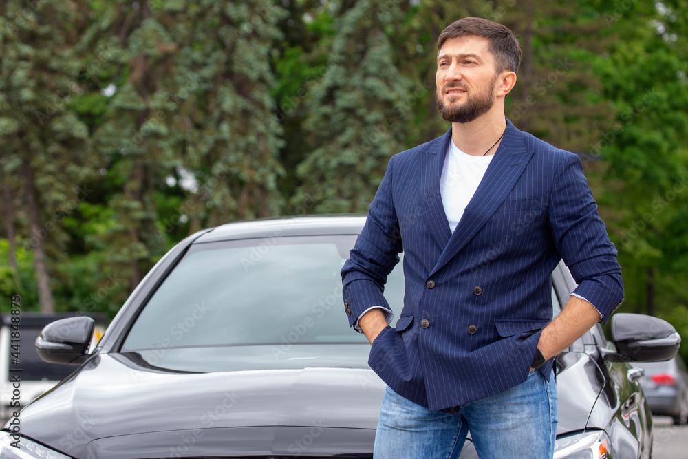 successful businessman is standing near his prestigious car