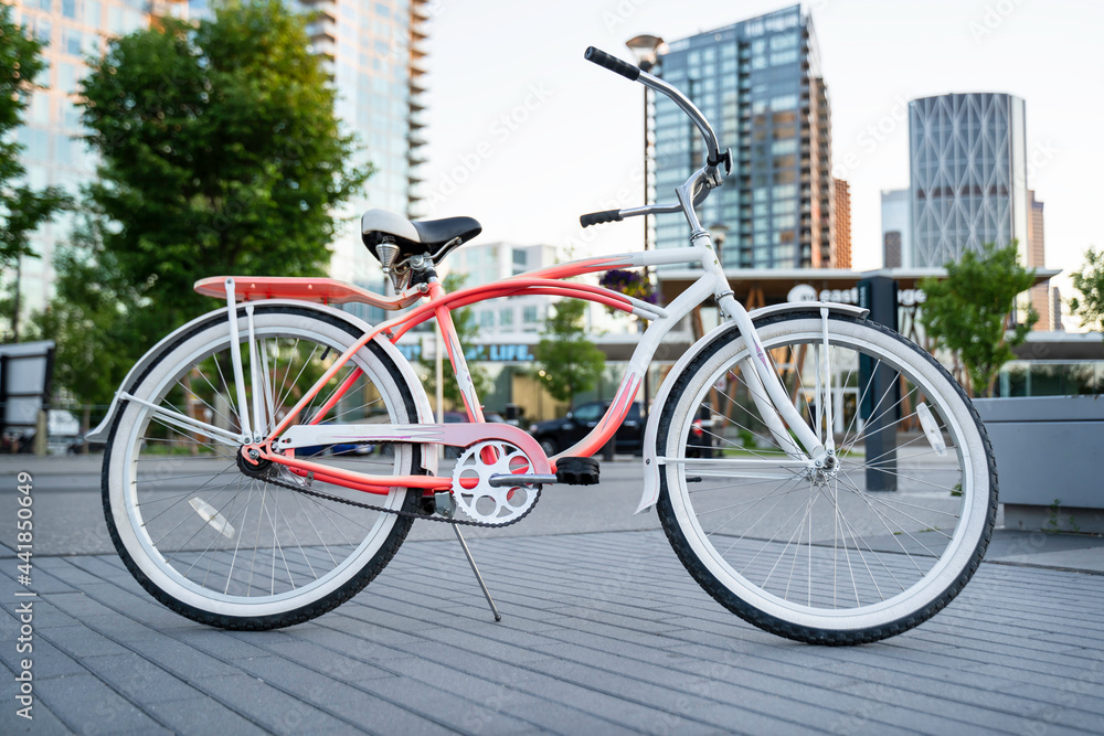 A vintage beach cruiser bike parked on a popular pedestrian pathway at East Village in downtown Calgary Alberta Canada on a summer evening.