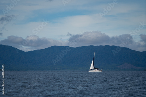 Sailboat in the sea in the evening sunlight over beautiful big mountains background. Adventure, active vacation concept 