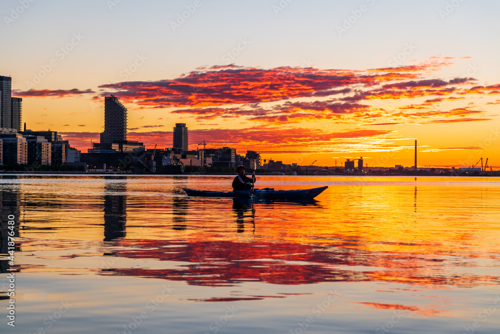 A sea kayaker crossing Toronto's Inner Harbour just as the rising sun breaks the horizon.