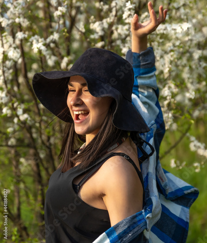 Portrait of a stylish girl among flowering trees in the forest.
