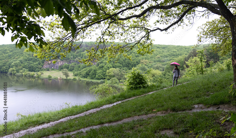Obraz premium A girl under an umbrella in the forest among the mountains.