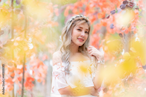 Portrait beautiful woman tourist posing happiness with smile ,she wearing a nice dress to travel in garden colorful flowers blooming for a summer vacation with beautiful flower garden background.