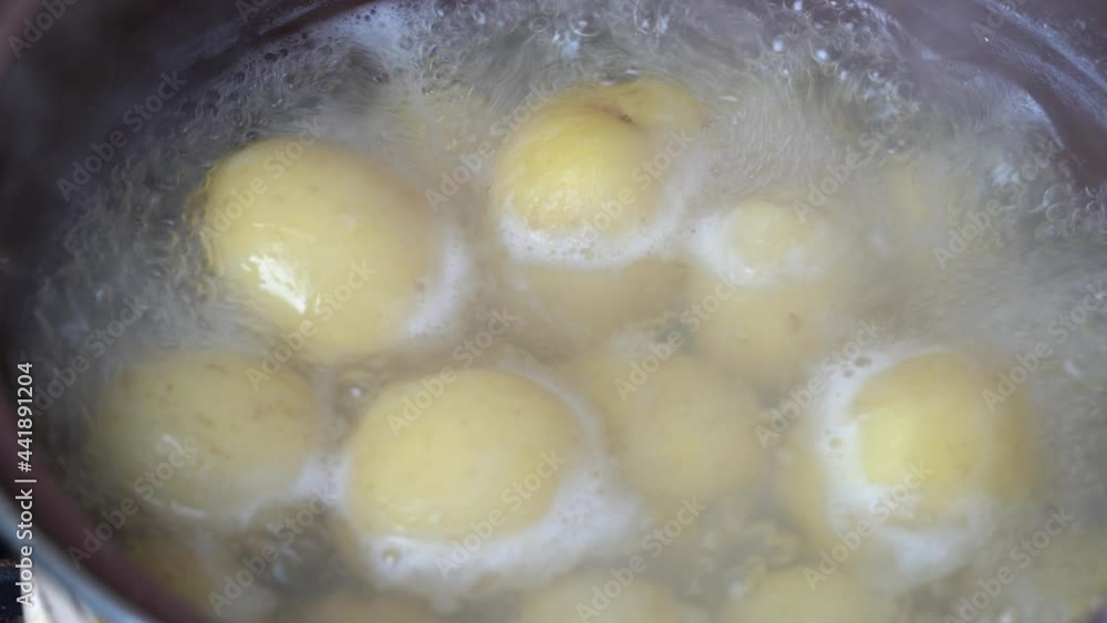 Close-up view of boiling water with yellow raw potatoes in a saucepan. Young potato are boiled in boiling water Close-up view of boiling water with yellow raw potatoes in a saucepan. Young potato are boiled in boiling water