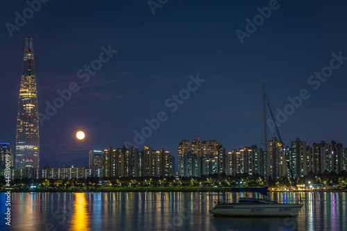 서울 한강의 스카이라인과 배, 보름달이 반짝이는 야경