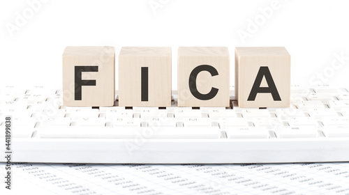 word FICA made with letters on the wooden blocks on the laptop photo