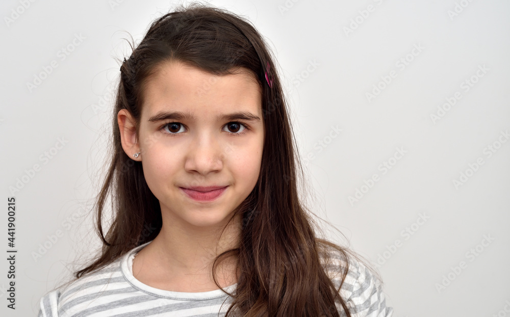 Portrait of a cute smiling young girl isolated on the grey background. Copy space on the right side Portrait of a cute smiling young girl isolated on the grey background. Copy space on the right side