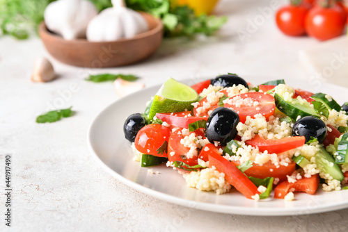 Plate with couscous and vegetables on light background, closeup