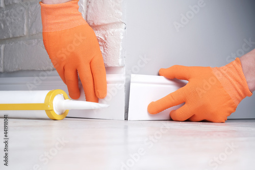 Fotografie Installation of skirting boards, master glues  floor plinth to  outer corner of
