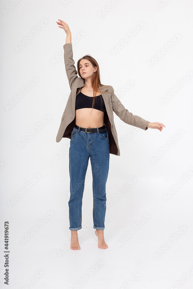 portrait of young caucasian attractive woman with long brown hair in blue jeans, black top and suit jacket on white background. skinny pretty lady posing at studio with bare feet portrait of young caucasian attractive woman with long brown hair in blue jeans, black top and suit jacket on white background. skinny pretty lady posing at studio with bare feet