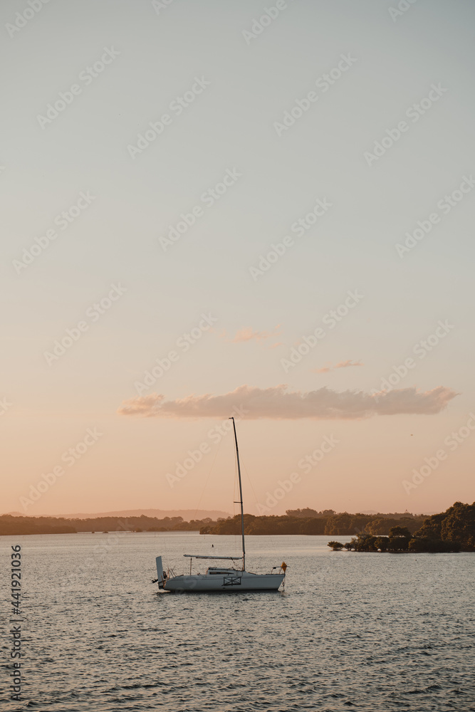 A boat sitting on the calm river at sunset near the Yamba Marina on the Clarence River.