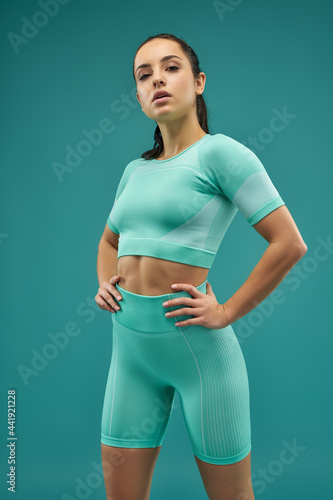 Attractive sporty woman standing against green background