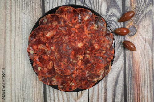 Portion of 100% acorn-fed Iberian chorizo from Extremadura decorated with acorns on wooden background