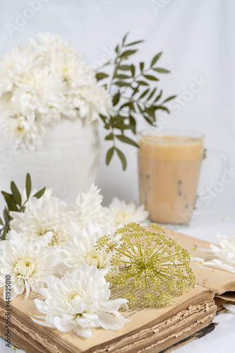 Still life with an old book  a cup of coffee and chrysanthemum flowers
