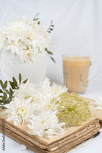 Still life with an old book, a cup of coffee and chrysanthemum flowers