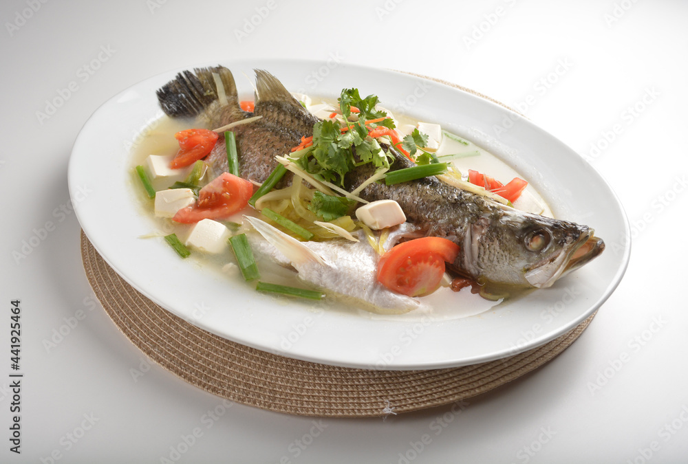 chef cook steamed fresh whole grouper fish with tofu beancurd, tomato, sour vegetable and ginger in teo chew sauce style in plate on white table restaurant asian cafe halal chinese banquet menu chef cook steamed fresh whole grouper fish with tofu beancurd, tomato, sour vegetable and ginger in teo chew sauce style in plate on white table restaurant asian cafe halal chinese banquet menu