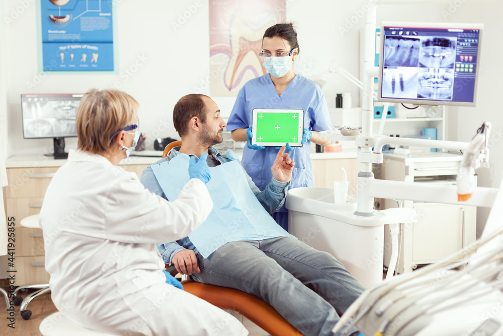Medical nurse holding mock up green screen chroma key tablet with isolated display during somatology consultation. Sick patient sitting on dental chair waiting for somatology x-ray scan Medical nurse holding mock up green screen chroma key tablet with isolated display during somatology consultation. Sick patient sitting on dental chair waiting for somatology x-ray scan
