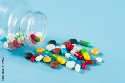 Assorted pharmaceutical medicine pills, tablets and capsules on blue background
