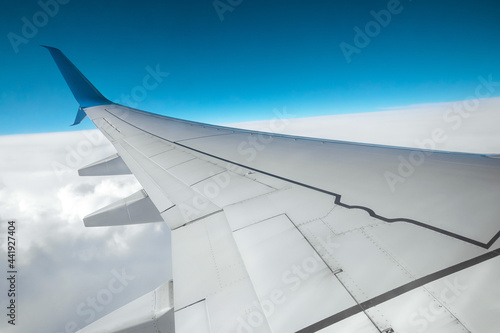 A wing of a modern passenger airplane above the clouds. International cargo transportation, air travel, transport. Copy space.