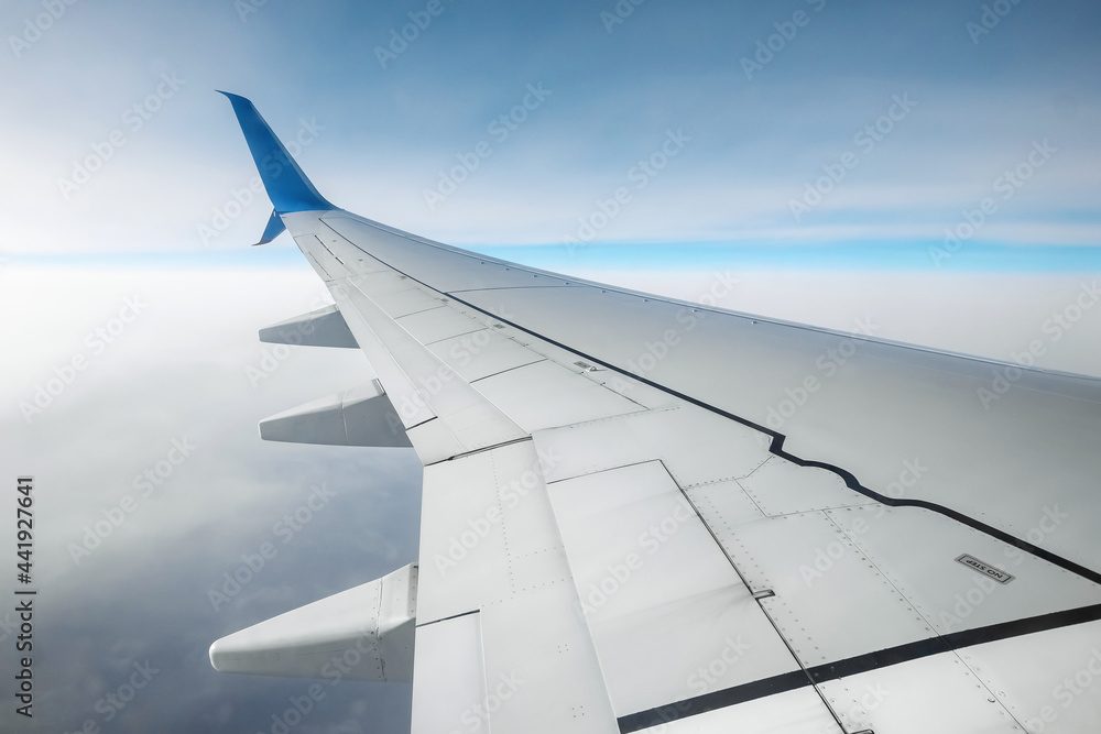 A wing of a modern passenger airplane above the clouds. International cargo transportation, air travel, transport. Copy space.