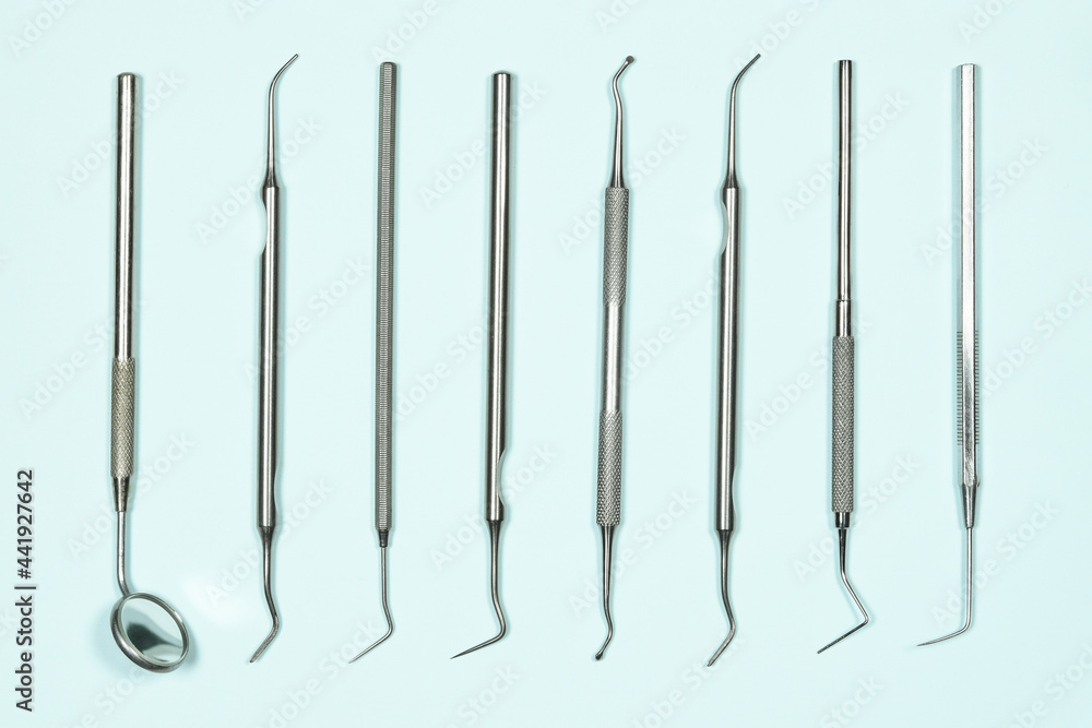 Some medical dental tools on light blue background. Flat lay closeup top view on dental instruments. Dental probes and explorers with mirror Some medical dental tools on light blue background. Flat lay closeup top view on dental instruments. Dental probes and explorers with mirror
