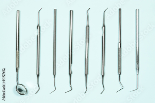 Some medical dental tools on light blue background. Flat lay closeup top view on dental instruments. Dental probes and explorers with mirror