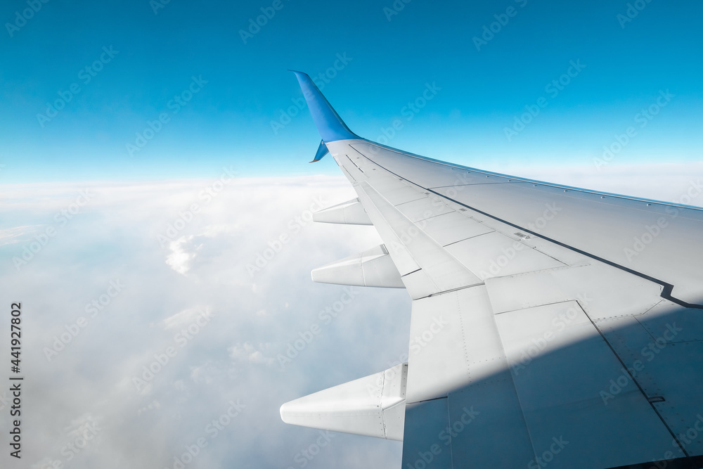 A wing of a modern passenger airplane above the clouds. International cargo transportation, air travel, transport. Copy space. A wing of a modern passenger airplane above the clouds. International cargo transportation, air travel, transport. Copy space.