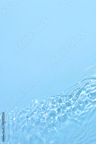 Transparent blue colored clear water surface texture with ripples, splashes and bubbles. Abstract nature background Water waves in sunlight with copy space Cosmetic moisturizer micellar toner emulsion © Aleksandra Konoplya