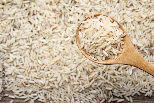 Organic raw rice in wooden spoon on old wood desk background 