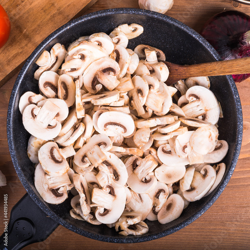 Raw chopped champignons in a pan for cooking fried mushrooms - a healthy vegetarian dish with vegetable protein.