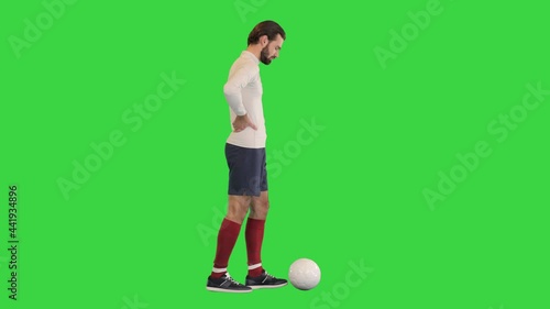 Football player walking slowly and kicking the ball on a Green Screen, Chroma Key. photo