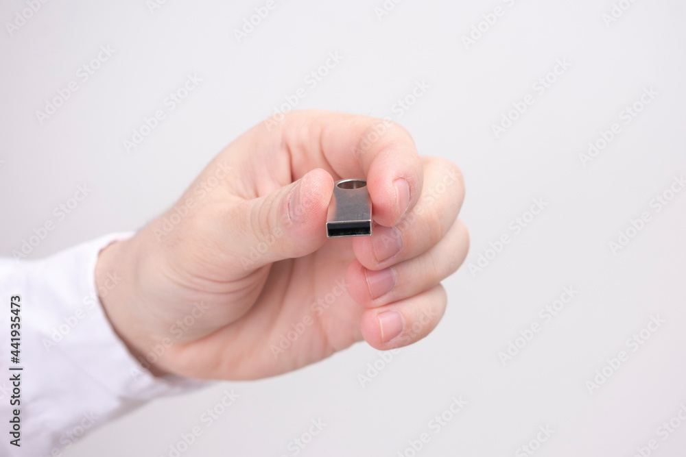 A man shows a USB flash drive connector, hand holding a USB flash drive on a white background, copy space A man shows a USB flash drive connector, hand holding a USB flash drive on a white background, copy space