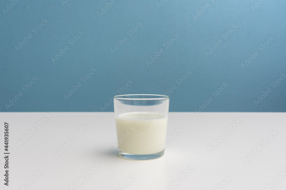 One glass of fermented milk drink, blue background, cropped image, close-up, copy space One glass of fermented milk drink, blue background, cropped image, close-up, copy space