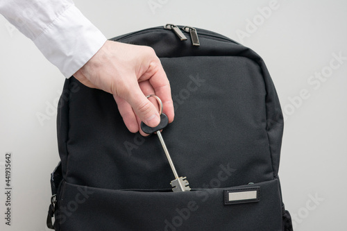 Man's hand with key to the apartment and backpack, man takes a key to the apartment, white background, cropped image, copy space