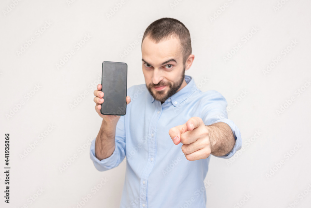 Cheerful bearded man with phone points finger at you, portrait, white background Cheerful bearded man with phone points finger at you, portrait, white background