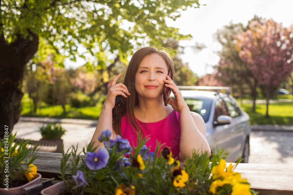 The happy woman is talking the phone at the outdoors cafe The happy woman is talking the phone at the outdoors cafe