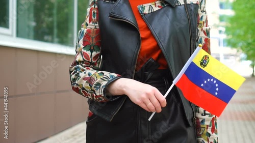 Unrecognizable woman holding Venezuelan flag. Girl walking down street with national flag of Venezuela