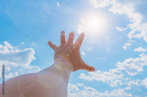 The hand of a man trying to reach the sun and heaven
