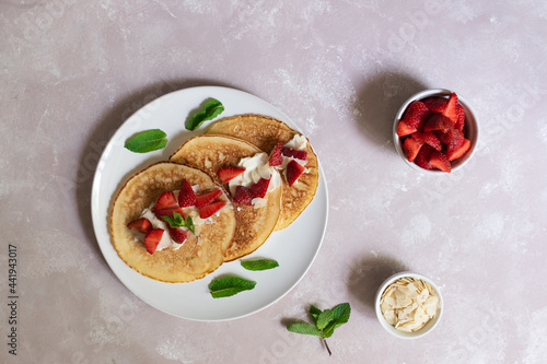 Pancakes with strawberry, cream cheese, almond flakes, mint on the light background