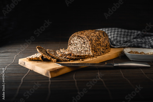 Gesundes Low Carb Brot ohne Mehl, Hefe und Sauerteig auf Holzbrett mit Messer vor dunklem Hintergrund photo