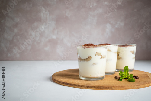 Traditional italian dessert tiramisu in glasses on the light background